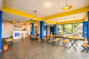 Un restaurante con mesas y sillas en una sala. en Shalom Backpackers Dharamkot McLeodganj, en McLeod Ganj