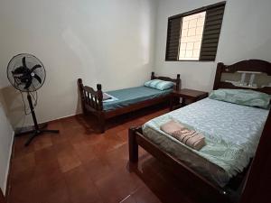 多拉杜斯Casa Parque Alvorada com garagem e ar Condicionado的一间卧室配有两张床和风扇