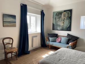 une chambre avec un canapé, une chaise et une fenêtre dans l'établissement ancienne poste de Saint coulomb, à Saint-Coulomb