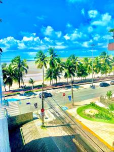 a view of a street with palm trees and a beach at hotel Green Sunset 406 in João Pessoa