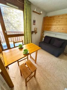 a living room with a table and a couch at Studette avec balcon parking et casier à ski 2 min du Jandri 3S aux 2 Alpes in Les Deux Alpes