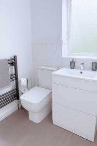 a white bathroom with a toilet and a sink at Spacious 3-Bed Contractor-Friendly Home in Bristol