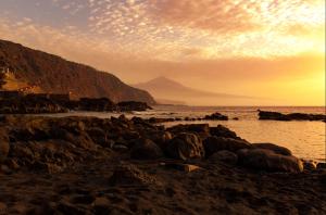 a beach with rocks and the ocean at sunset at Brisa del Mar in Tacoronte