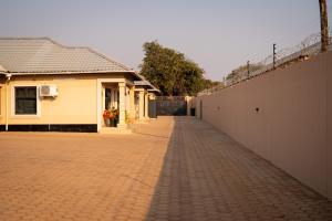 a brick road next to a building and a fence at RJV Apartments, Meanwood Ibex Hill, Lusaka in Lusaka +7 photos