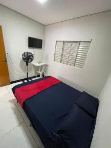 a bedroom with a bed with a red and blue blanket at Suítes Família Imperial in Uberlândia