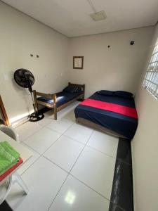 a small room with a bed and a fan at Suítes Família Imperial in Uberlândia