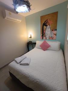a bedroom with a white bed with a painting on the wall at Art Hotel Getsemani in Cartagena de Indias +5 photos
