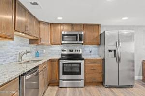 パナマ・シティ・ビーチにあるFall Special 4br Ocean Views Sounds Pickle Ballのキッチン(ステンレス製の電化製品、木製キャビネット付)