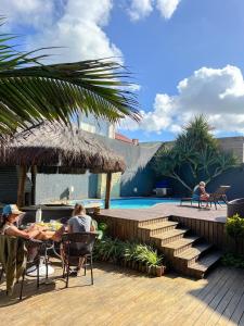two people sitting at a table near a swimming pool at Pier Beach Club in Cabo Frio