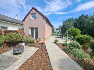 a backyard with a pink house and flowers at Garden House Slavkov in Veľký Slavkov
