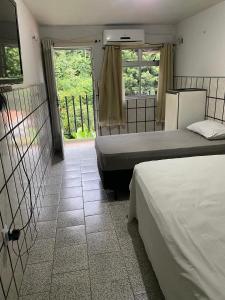 a bedroom with two beds and a door with a window at Hotel Cascata in Tianguá