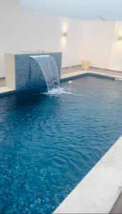 a swimming pool with a water fountain in a building at Apt 5min de la zone touristique avec piscine Residence Jude in Hammamet