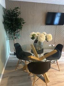 a dining room with a table with chairs and a vase of flowers at Adult only, fetish retreat play space in Ifield