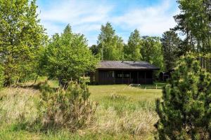 eine Scheune inmitten eines Feldes mit Bäumen in der Unterkunft L38 Rødby - Lærkevænget 10 in Rødby