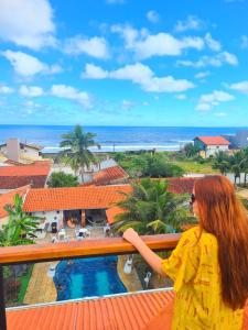 a woman standing on a balcony looking at the ocean at Hostel Praia Centro Itanhaém in Itanhaém