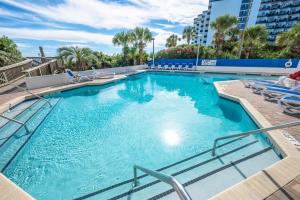 a large swimming pool with blue water and lounge chairs at Pets welcome,direct oceanfront, poolside,1 bedroom in Myrtle Beach