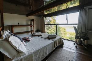 a bedroom with a bed and a large window at Vista para o Mar Dunas e Lagoa em Garopaba in Garopaba