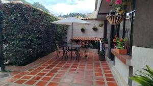 a patio with a table and chairs and an umbrella at El Encanto de Sopo in Sopó