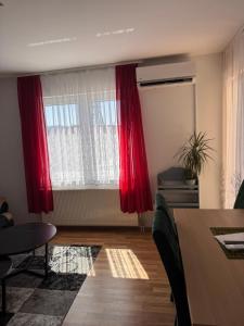 a living room with red curtains and a table at Beauty Room Apartman in Prnjavor