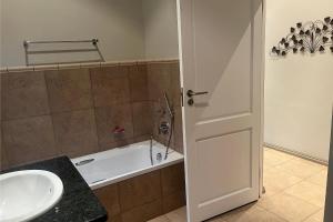 a bathroom with a tub and a sink and a white door at Aleah, Cathkin Estates by Euphoric Leisure in Champagne Valley +28 photos