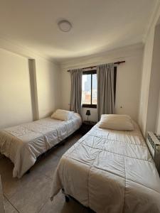 Un dormitorio con dos camas y una ventana. en Departamento Caseros, en Salta
