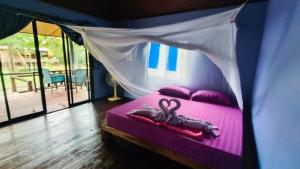 a bedroom with a pink bed with a canopy at BMB Boun Marvin Payham Bungalows in Ko Phayam