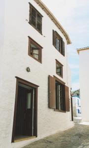 a white building with brown windows and a door at Alleyway House in Hydra