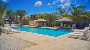 a swimming pool with lounge chairs and umbrellas at 3-Suite Condo Steps to Palm Beach in Palm-Eagle Beach