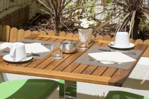 a wooden table with plates and utensils on it at Cristal Hôtel & Spa in Cannes