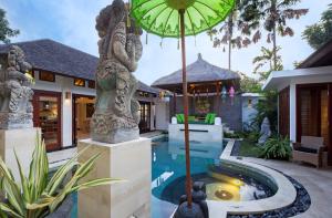 a villa with a swimming pool and an umbrella at Villa Zamaya Sanur in Sanur