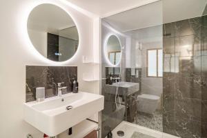 un bagno bianco con lavandino e specchio di L'Ermitage a Rambouillet Altre 26 foto