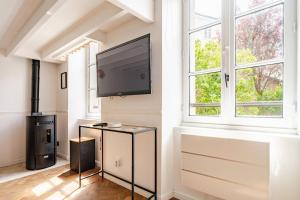 un soggiorno con una TV a schermo piatto su una parete di L'Ermitage a Rambouillet