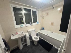 a bathroom with a sink and a toilet and a bath tub at Stunning 5 Bedroom Home in the Heart of Swansea - Snooker Table, WiFi & Parking! in Swansea