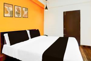 a bedroom with a white bed and an orange wall at Super Collection O Banaswadi in Bengaluru +25 photos