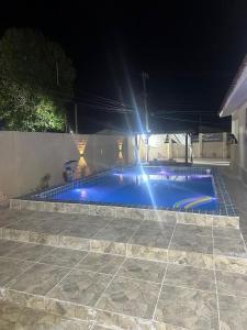 ein blauer Pool in der Nacht mit Lichtern in der Unterkunft CasAMAR - casa de praia na terra das piscinas naturais - PE in São José da Coroa Grande