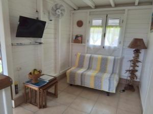a living room with a couch and a tv and a table at Le Jardin aux Oiseaux in Sainte-Anne