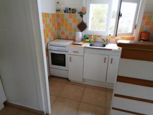 a small kitchen with white cabinets and a sink at Le Jardin aux Oiseaux in Sainte-Anne