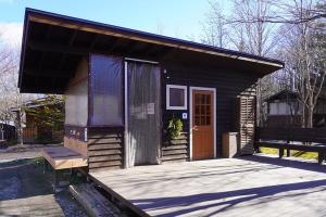 a small cabin with a wooden porch and a door at Kitakaruizawa Sweet Grass - Vacation STAY 18432v in Kita-karuizawa