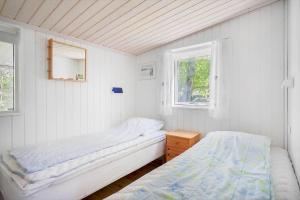 a white room with two beds and a window at 20399-Samso-Laerkevej-24 in Nordby