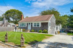 a small white house with a fence and a yard at Walk to Beach Quaint Dennis Home with Deck and Grill! in Dennis