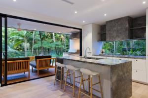 an open kitchen with a large island with bar stools at Luxury rainforest retreat, Little Cove in Noosa Heads