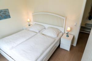 a white bed with two lamps on two tables at Zimt & Zucker in Langeoog