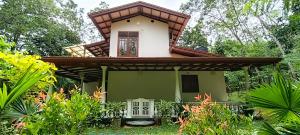 a small green and white house in a garden at Sanduhan Villa in Warakapola
