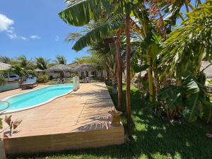 a pool with a wooden deck next to a resort at Casa Praia in Luis Correia