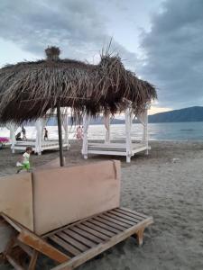 a straw umbrella and a chair on a beach at Tonia&Sion in Vlorë