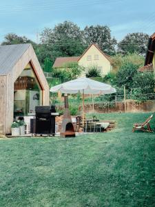 a grill and an umbrella in a yard at Tinyhouse mit Pelletofen in Wertheim