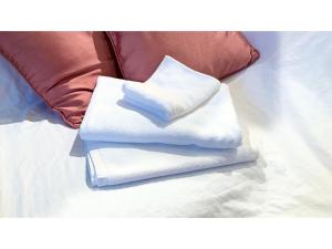 two stacks of white towels on a bed with pillows at Smile Hotel Naha City Resort - Vacation STAY 05994v in Naha