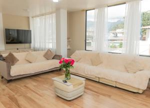 a living room with two couches and a vase of flowers at Bienvenue chez nous in Otavalo