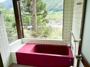 a red bath tub in a bathroom with a window at Washiki Shiki no Sato Cottage - Vacation STAY 03146v in Wajiki