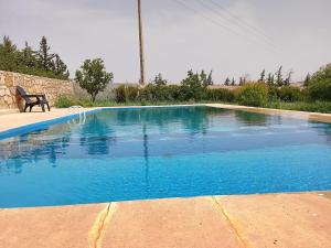 a blue swimming pool with a chair next to it at Tazouta Farm Villa with Private Pool & Mountain Views in Tazouta